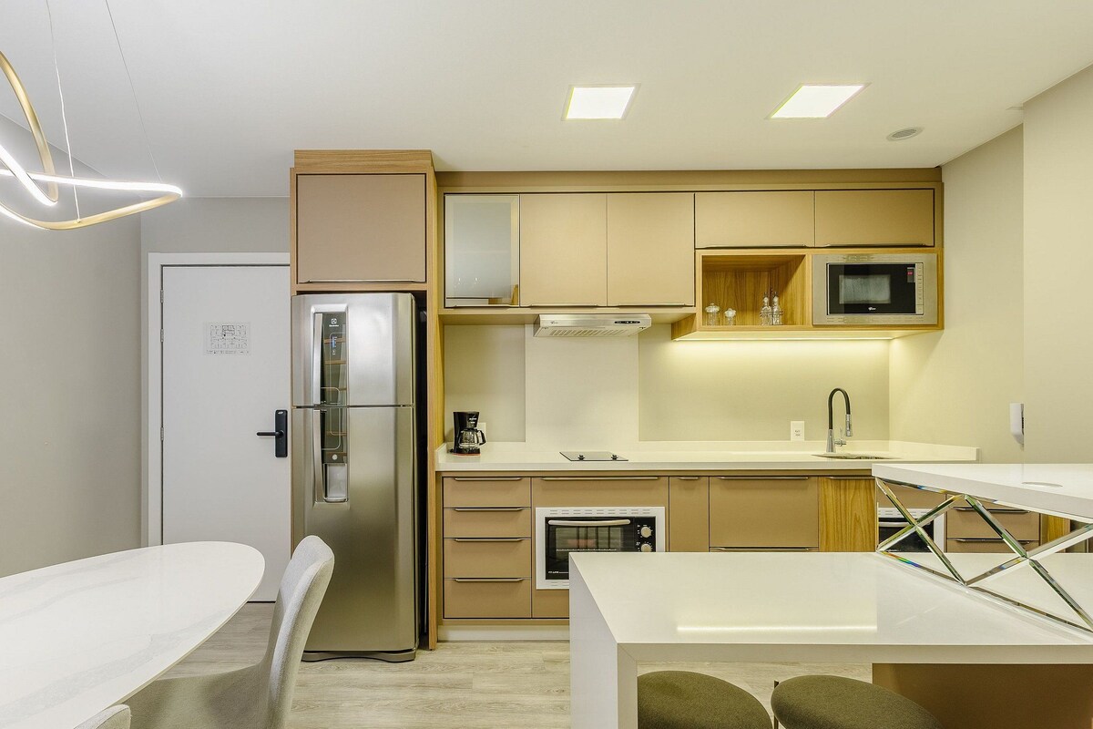 A modern kitchen with a built-in refrigerator, microwave, oven, and a coffee maker on the counter.