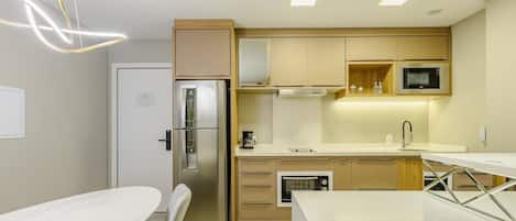 A modern kitchen with a built-in refrigerator, microwave, oven, and a coffee maker on the counter.