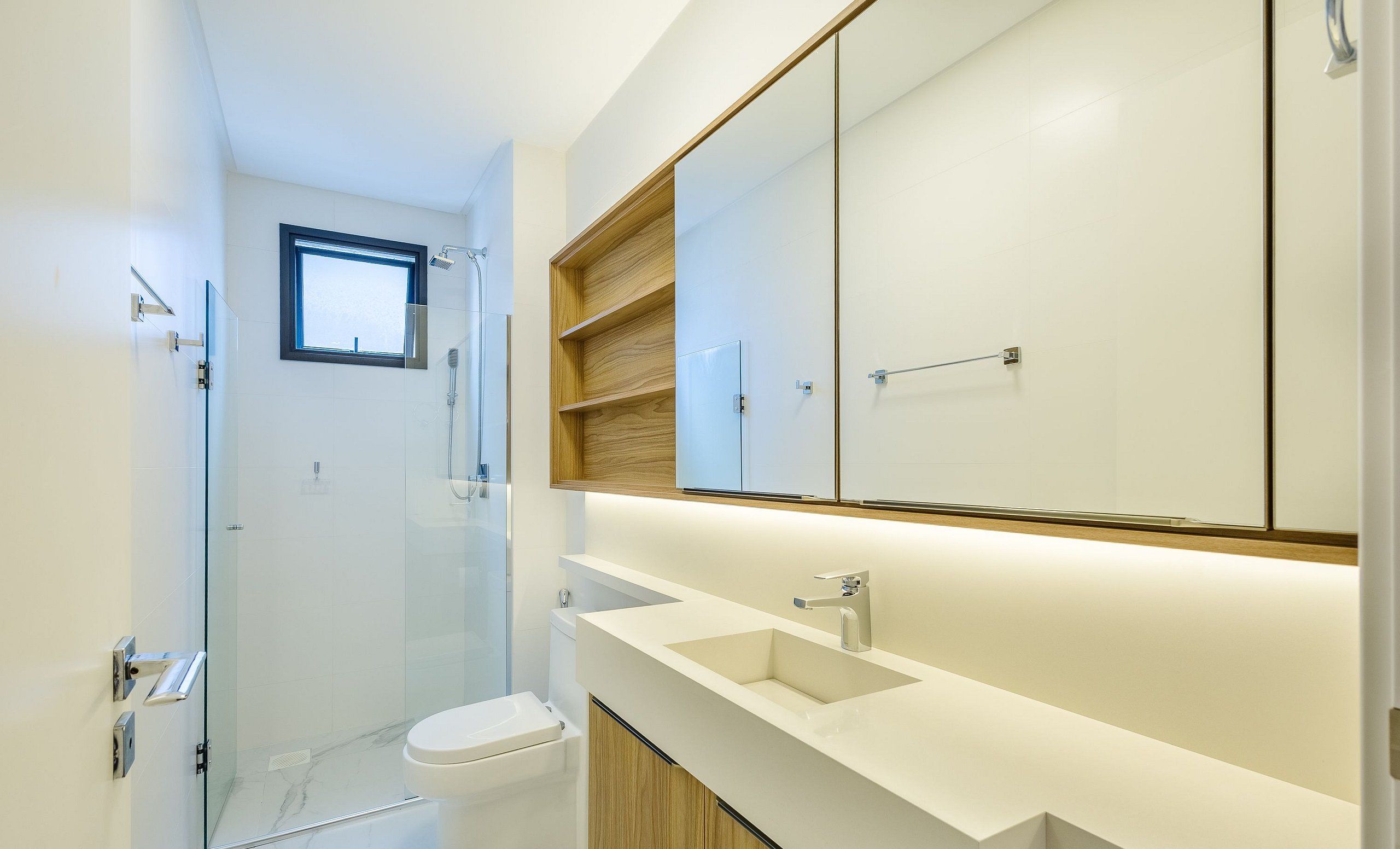 A modern bathroom with a glass shower enclosure, a toilet, a sink, and a large mirror.