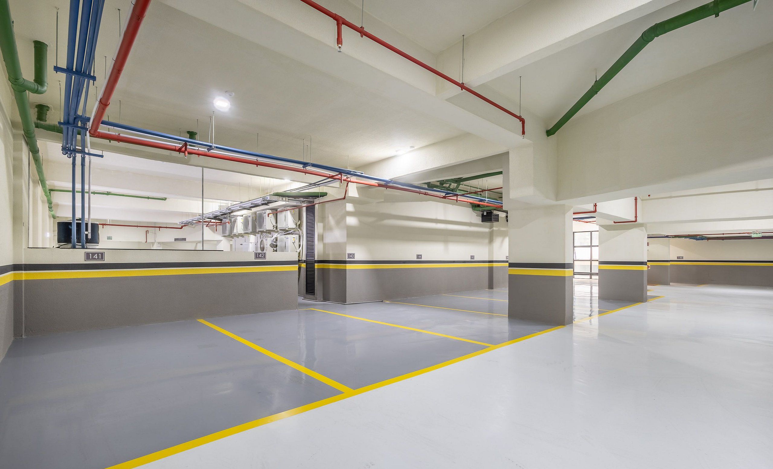 Un parking souterrain propre et bien éclairé, avec des marquages clairs délimitant les voies et des éléments de soutien structurels bien visibles.