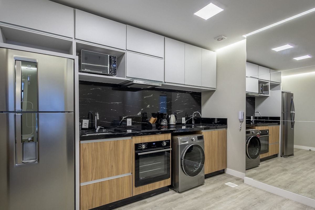 A modern kitchen with stainless steel appliances, a built-in oven, and a washing machine.