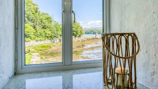 Una habitación con un amplio ventanal que ofrece vistas a un río y vegetación.