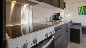 A modern kitchen with a built-in stove, oven, and sink. There is a coffee maker and a small table with a lamp. - 5 Person Holiday Park Home in Bryrup (Bryrup)