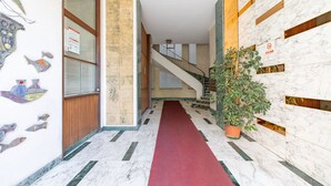Eine Hotelhalle mit Marmorboden, rotem Teppich, einer Treppe und einer Pflanze.
