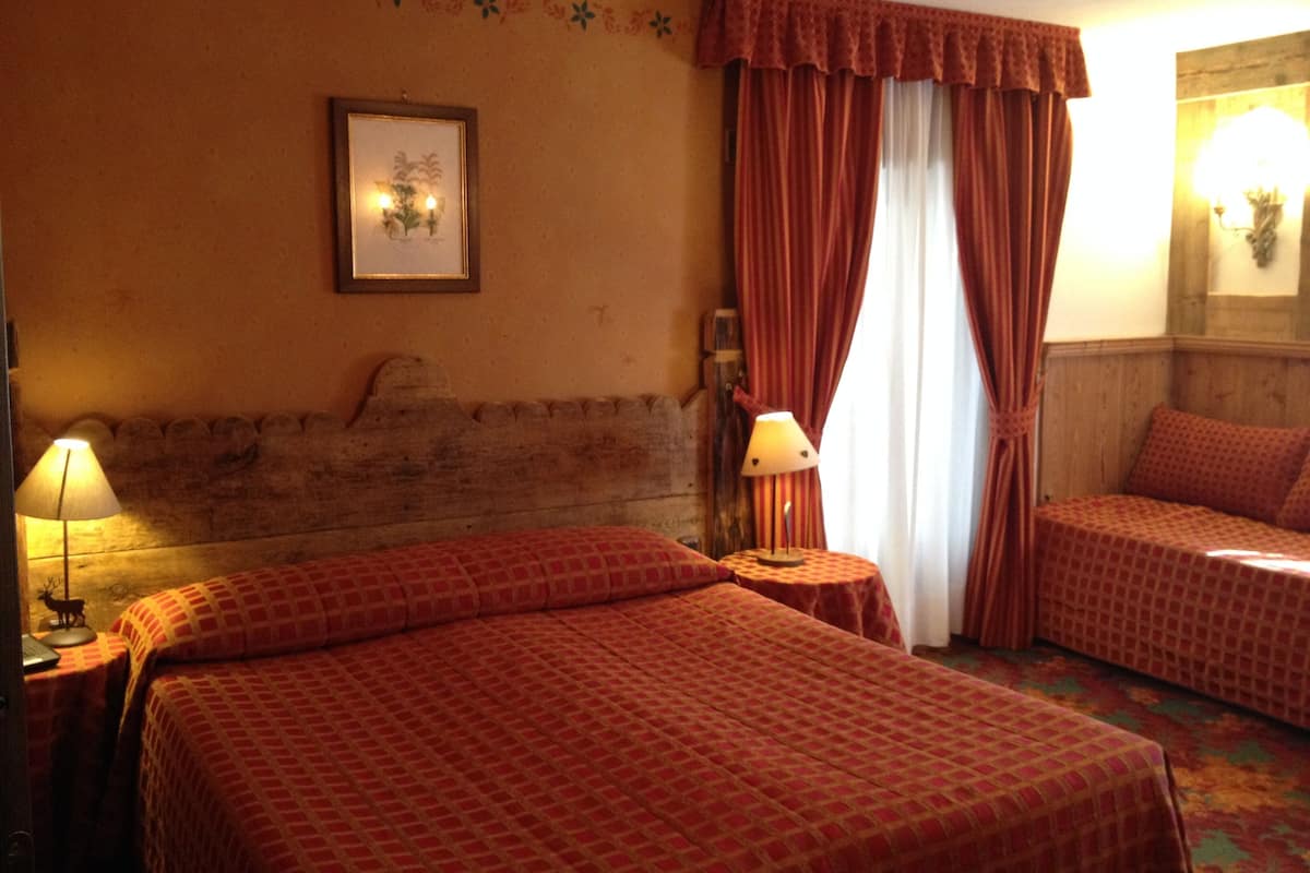Habitación de hotel con dos camas, cabecero de madera, un cuadro enmarcado en la pared y una ventana con cortinas.