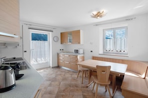 Una cocina moderna con comedor, microondas y hervidor.