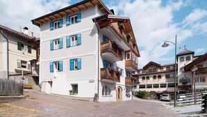 A multi-story building with balconies, a sign indicating a parking area, and a cobblestone street. - Apartment 'Vich' with Mountain View, Balcony and Wi-Fi (Vigo di Fassa)
