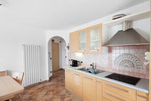 Una cocina con armarios de madera, un lavamanos de acero inoxidable, salpicadero de azulejos y un radiador.