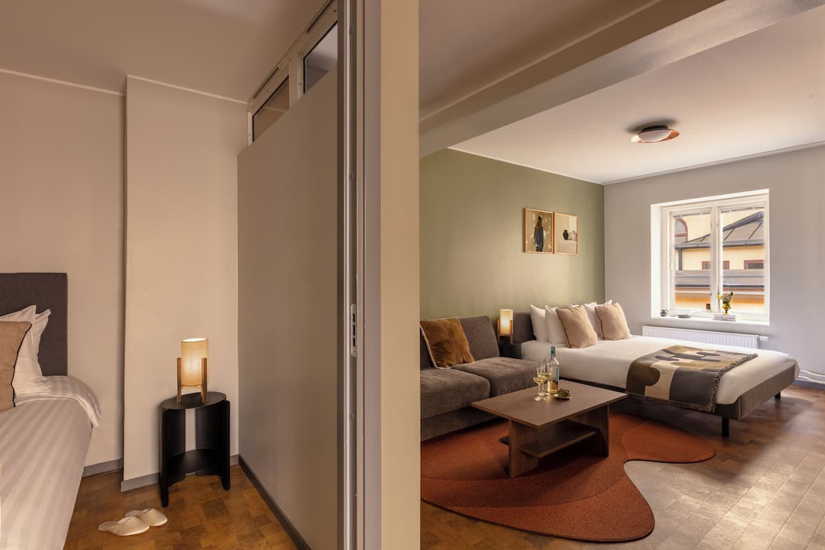 Une chambre d’hôtel avec un lit, un canapé, une table basse et une fenêtre donnant sur un beau paysage.