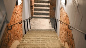 Una escalera con un muro de ladrillo a un lado y un muro blanco al otro, que conduce a una plataforma.