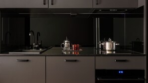 Una cocina moderna con un reloj digital, electrodomésticos de acero inoxidable y un diseño minimalista.