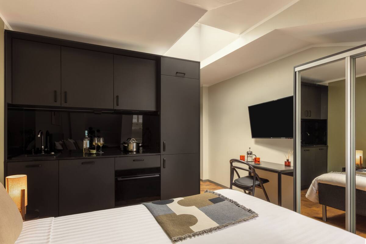 Une chambre d’hôtel moderne équipée d’un lit, d’un bureau, d’une kitchenette et d’une télévision.