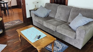 A living room with a grey sofa, wooden coffee table, and a blue patterned rug. - Watkins Glen Overlook Apt (Watkins Glen)