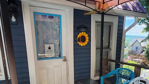 A covered porch with a door, a small table, and two chairs. - Watkins Glen Overlook Apt (Watkins Glen)