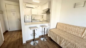 A compact kitchen with a refrigerator, sink, and two bar stools. - Apartment Apartsalou Michelangelo 2 (Salou)