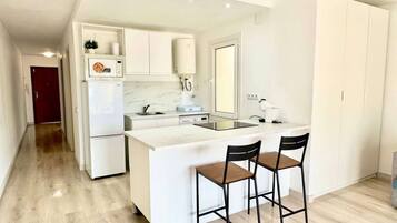 Een koelkast, een oven, kookgerei, borden en bestek