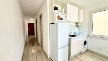 Een koelkast, een oven, kookgerei, borden en bestek