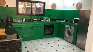 A kitchen with green cabinets, a black countertop, a window, and a washing machine. - HOUSE ROUTE DE L'OURIKA MARRAKECH (Marrakech)