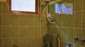 Un baño con inodoro, ventana y ducha.