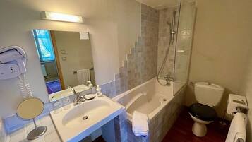 A bathroom with a sink, mirror, handheld showerhead, toilet, and a trash bin.