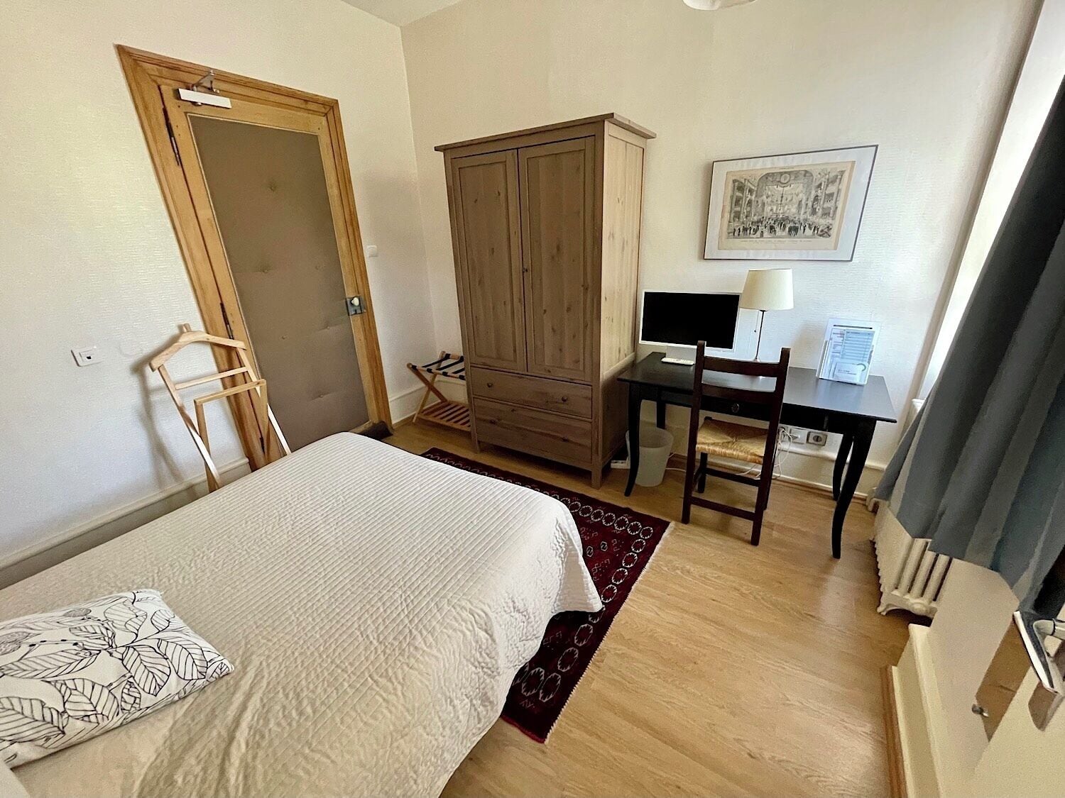 Un dormitorio con cama, escritorio con ordenador, armario y una silla.