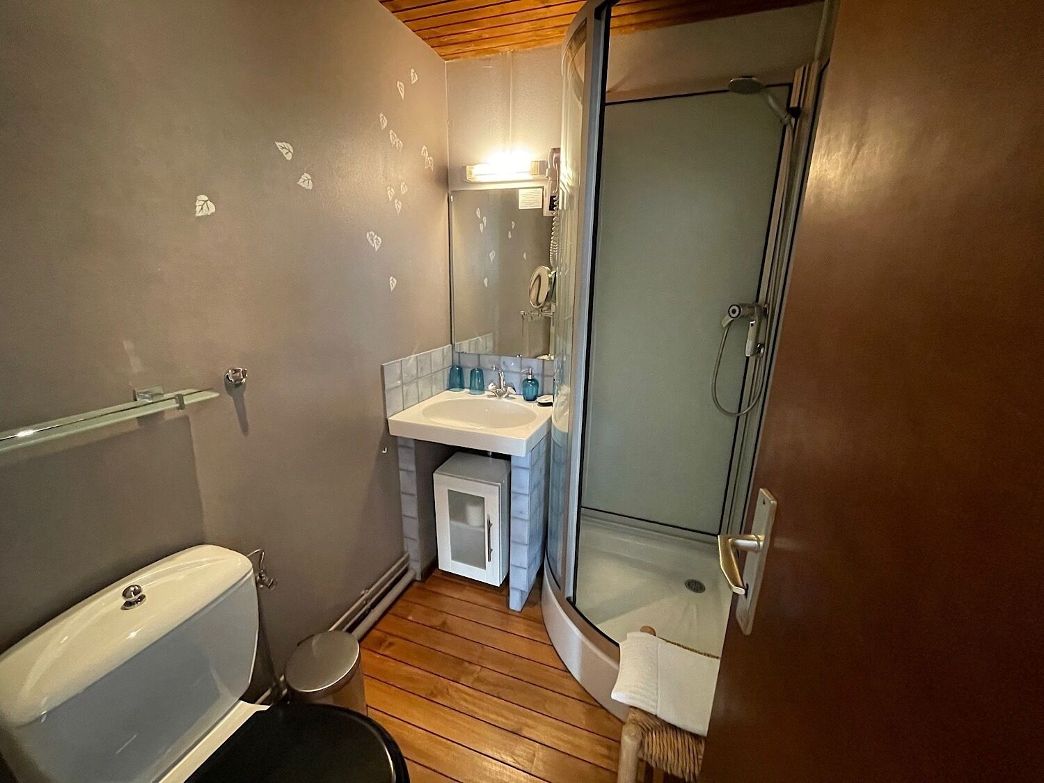 A compact bathroom with a toilet, sink, and shower.