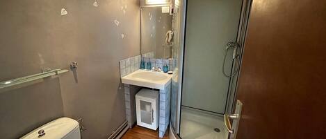 A compact bathroom with a toilet, sink, and shower.