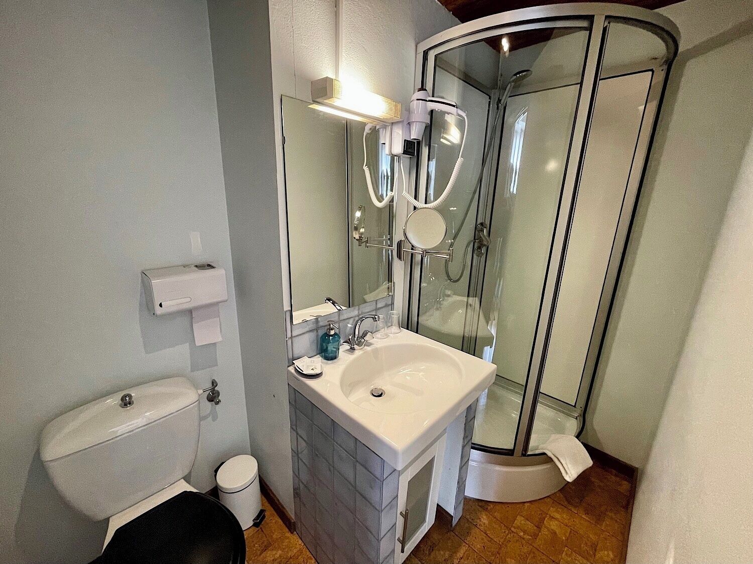A bathroom with a toilet, sink, and glass shower enclosure.