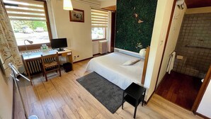 Une chambre à coucher comprenant un lit, un bureau, une chaise, un radiateur et une fenêtre avec des stores.