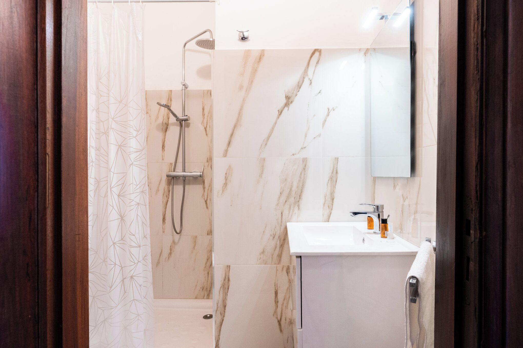 Un bagno moderno con doccia, lavandino e specchio.
