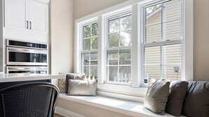A kitchen with built-in appliances, a window seat with cushions, and a view of the outside. - Cute and Quaint on Carrollton | Patio & Game Room (Indianapolis)