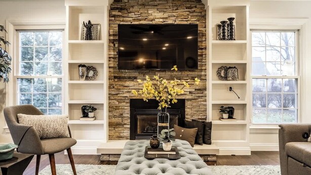 A living room with a stone fireplace, a flat-screen TV, and built-in shelving. - The Crestview Bungalow | Steps to Broad Ripple! (Indianapolis)