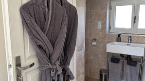 Un baño con un lavamanos blanco, un espejo y dos toallas colgadas en la pared.