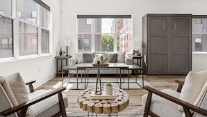 A modern living room with a sofa, coffee table, and a view of buildings outside.