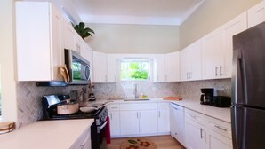 A modern kitchen with white cabinets, a stainless steel refrigerator, and a herringbone-patterned backsplash.