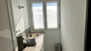 Una piccola cucina con lavandino, finestra e cestino.