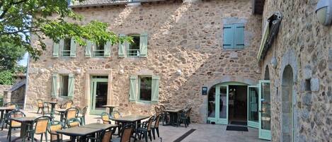 A stone building with outdoor seating and a covered entrance.
