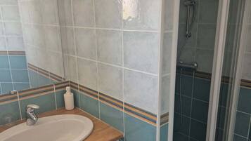 A bathroom with a sink, mirror, and shower.