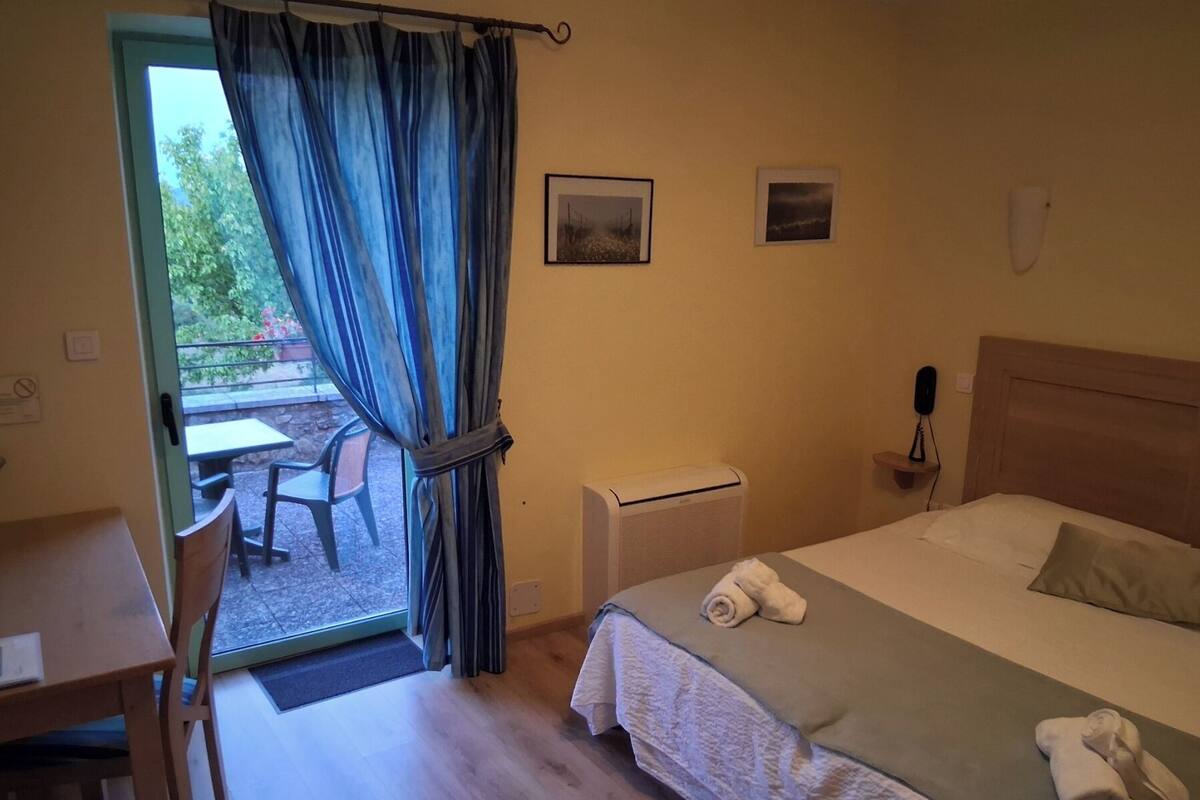 Habitación de hotel con cama, escritorio, silla y vistas al exterior.