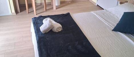 Una habitación con una cama, un escritorio y una silla. Hay toallas sobre la cama.
