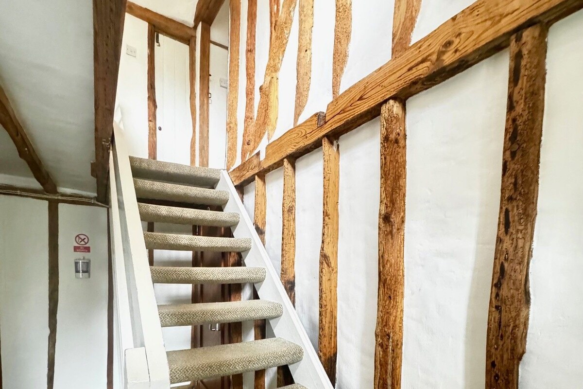 A staircase with wooden beams and carpeted steps.