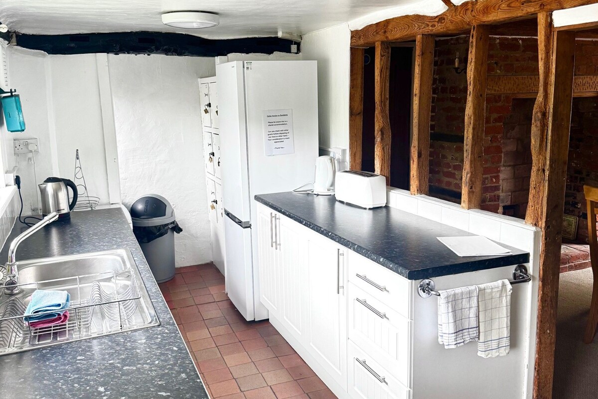 A compact kitchen with white cabinets, a black countertop, a stainless steel sink, and a white refrigerator.