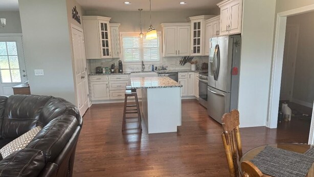 Una cocina moderna con armarios blancos, una isla central y un refrigerador de acero inoxidable.