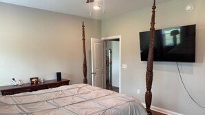 Un dormitorio con cama con dosel, un televisor de pantalla plana montado en la pared y un aparador de madera.