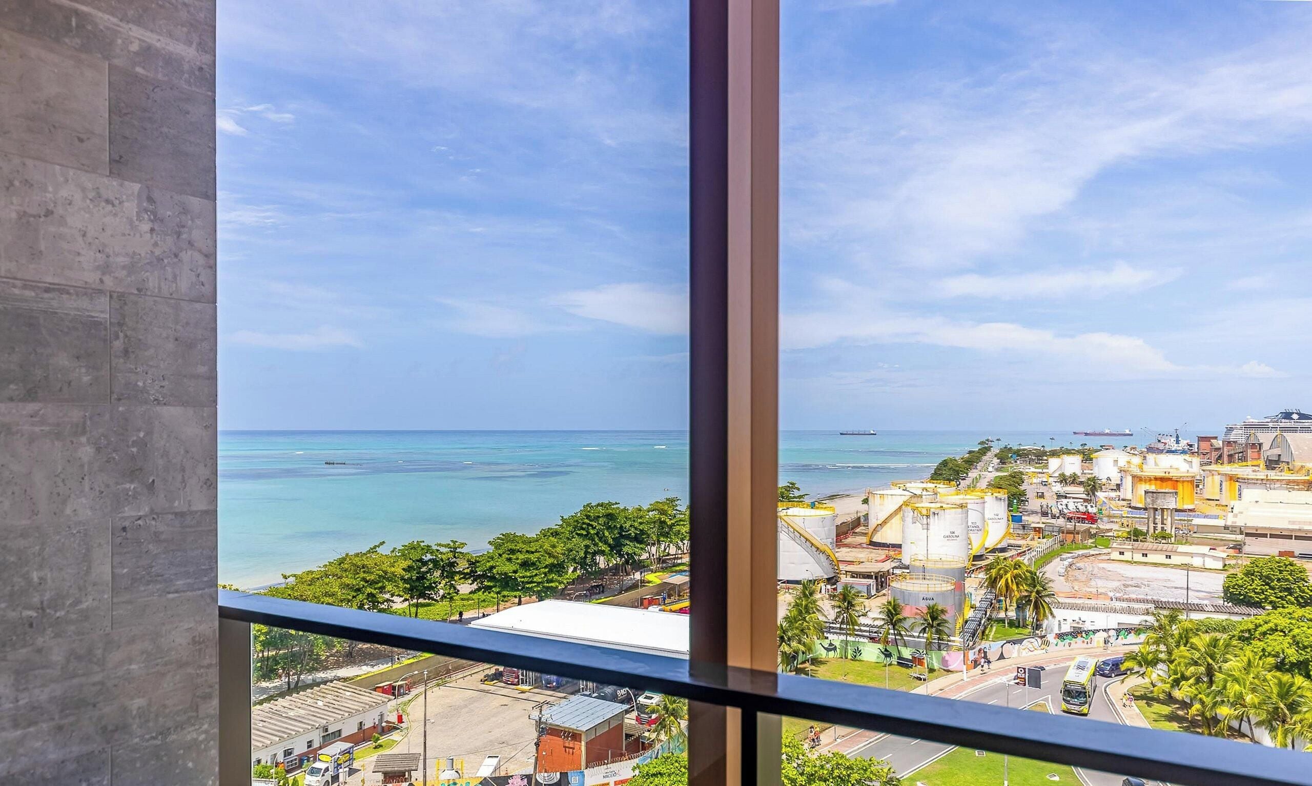 A view from a high-rise window overlooking a coastal city with a clear sky.