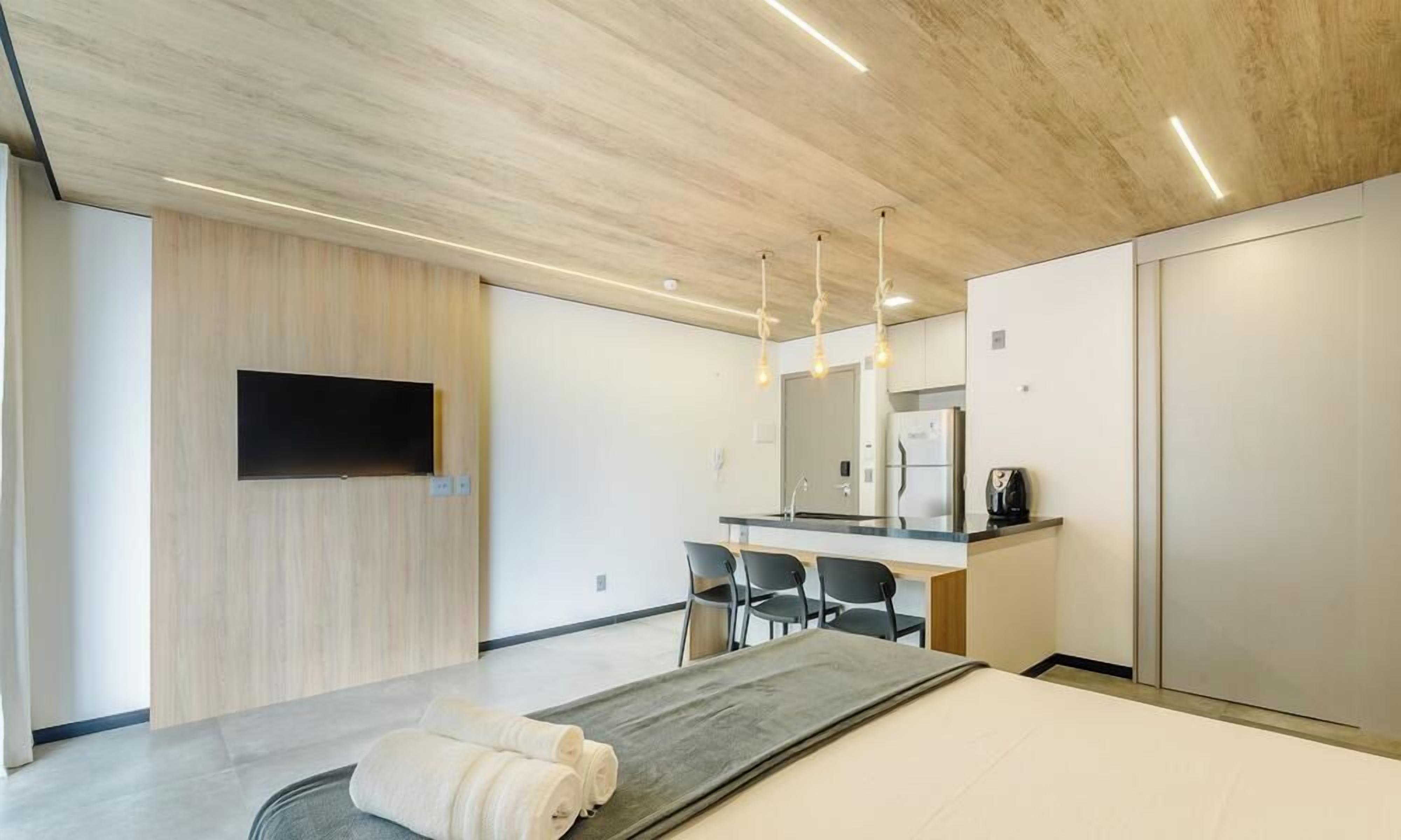 A modern hotel room with a bed, a desk, a flat-screen TV, and a large mirror.