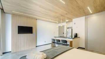 Habitación de hotel moderna con cama, escritorio, televisor de pantalla plana y un espejo grande.