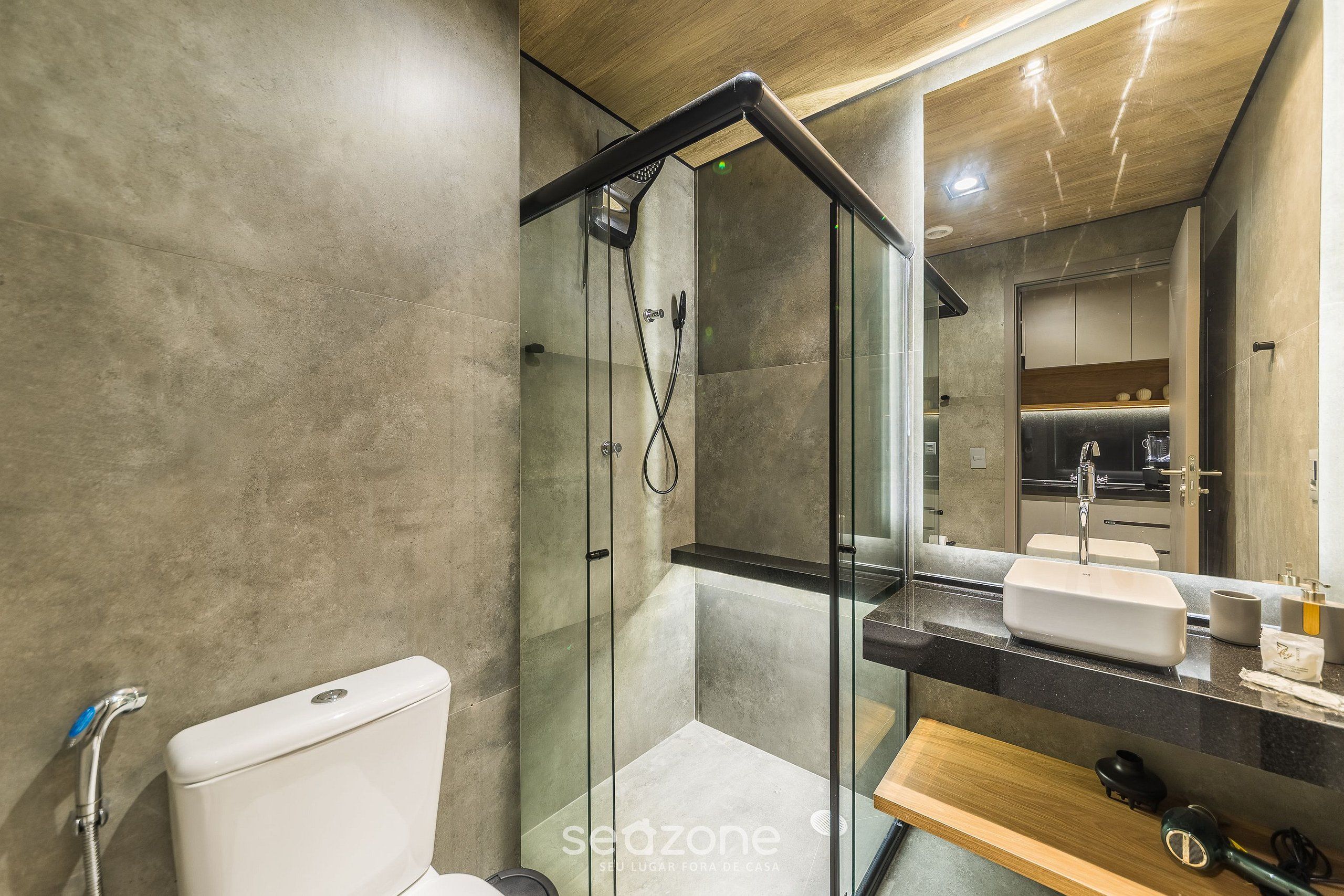 A modern bathroom with a glass-enclosed shower, a toilet, and a sink with a mirror above.
