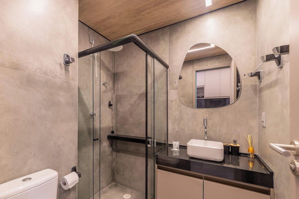 A modern bathroom with a glass shower enclosure, a toilet, a sink with a mirror, and a vanity.