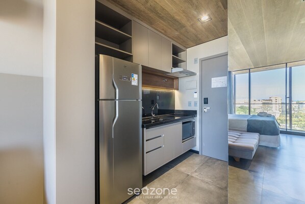 Eine moderne Küche mit Einbaukühlschrank, Backofen und Spüle. Ein großes Fenster bietet Blick auf die Stadt.